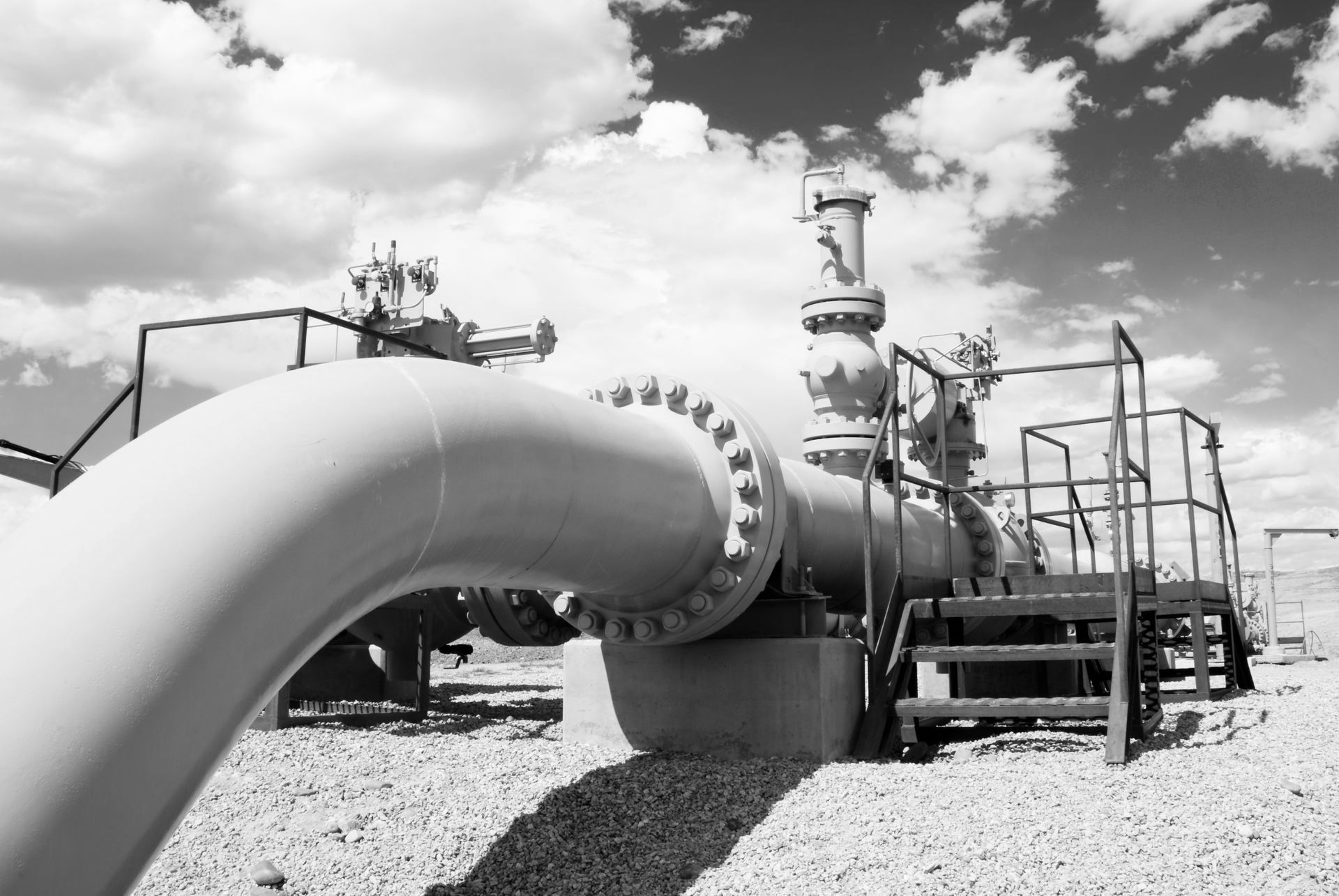 A black and white photo of a gas pipe in a field.